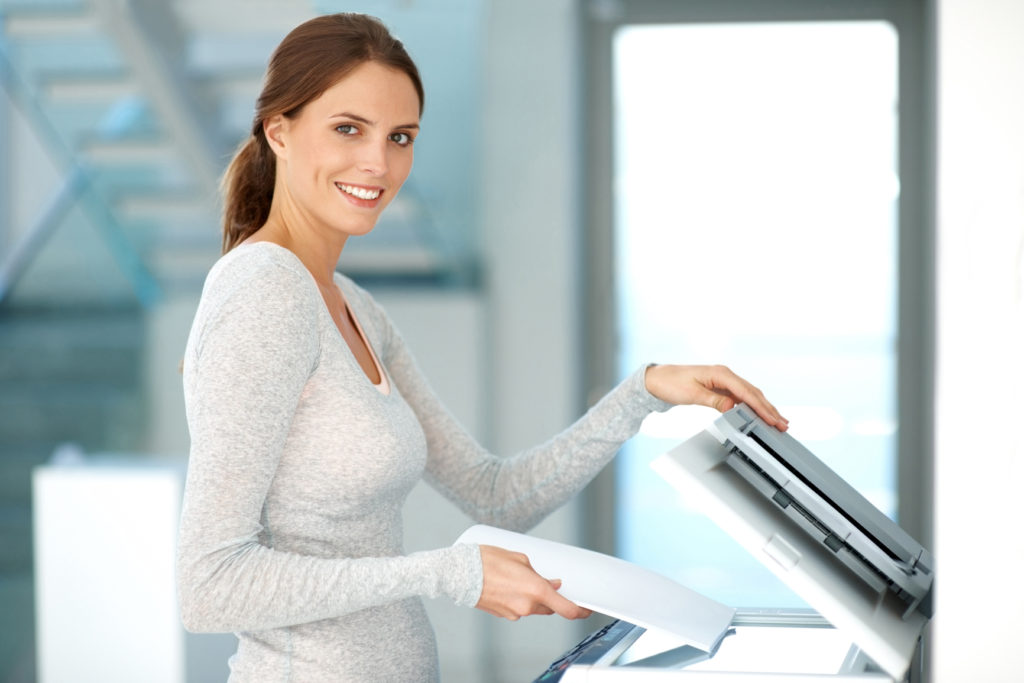 Pretty young businesswoman making copies on the photocopy machine  at the office